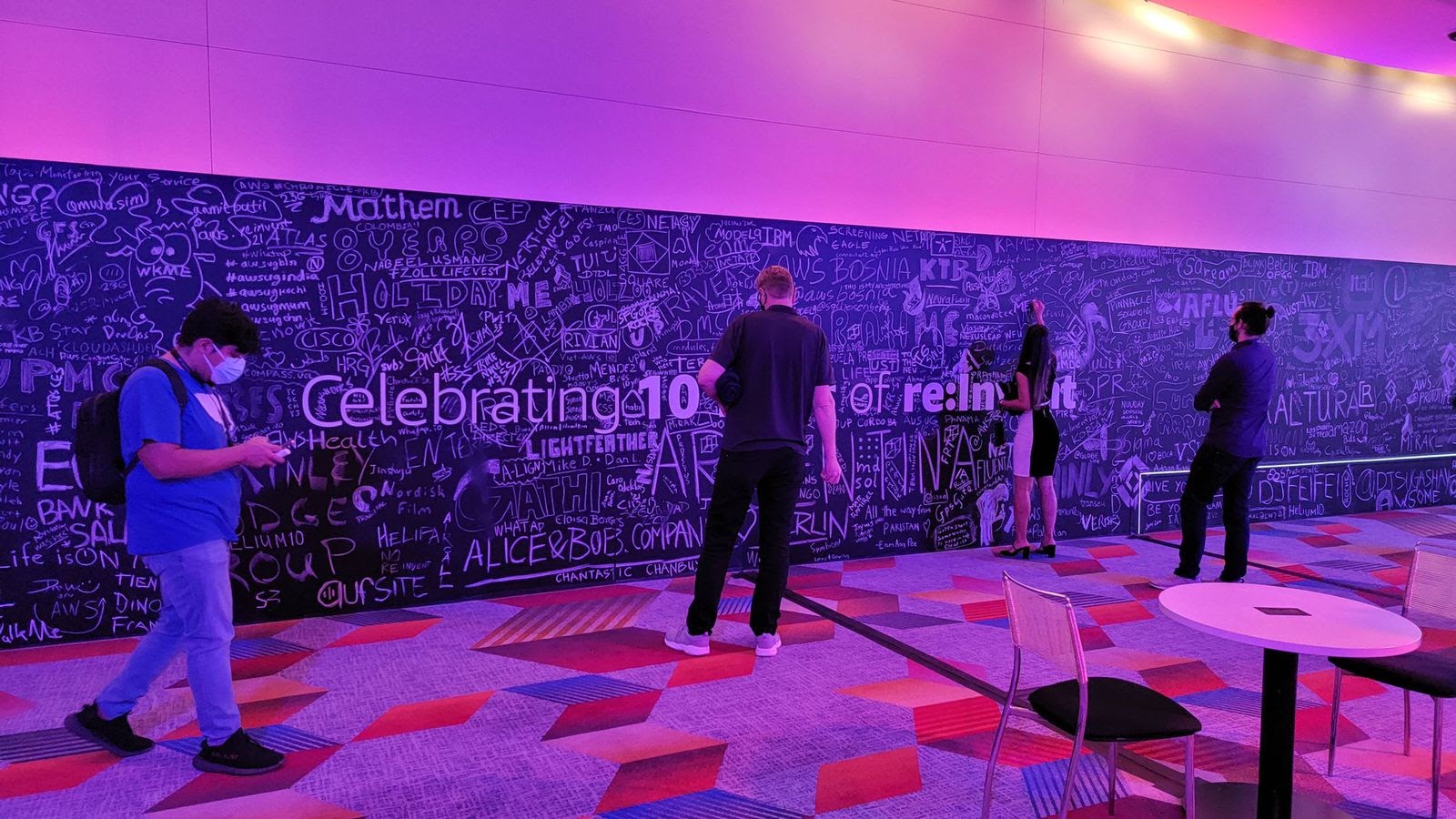 Photo of in-person attendees at AWS re:Invent 2021 writing their signatures on a blackboard. 